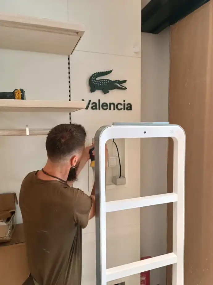 Trabajador de Aingenia colocando cámara de seguridad en tienda Lacoste